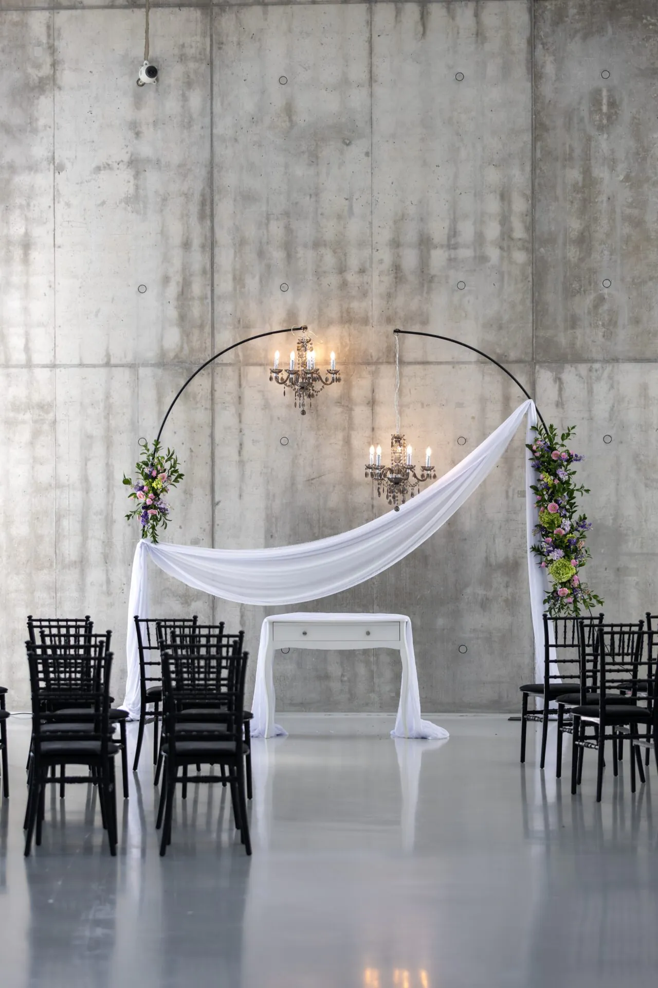 Elegantná svadobná výzdoba s čiernymi stoličkami a kvetinovým oblúkom