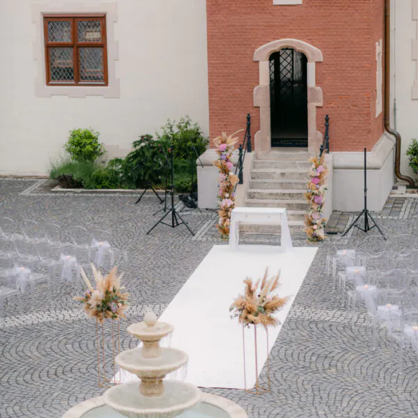 Vonkajšia svadobná výzdoba s bielym kobercovým chodníkom a kvetinovými aranžmánmi