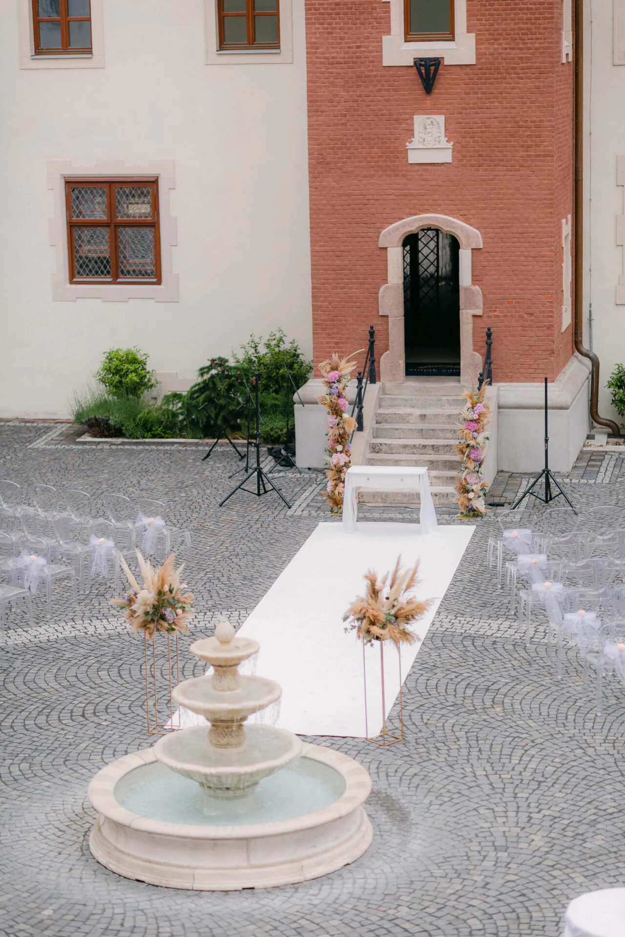 Vonkajšia svadobná výzdoba s bielym kobercovým chodníkom a kvetinovými aranžmánmi