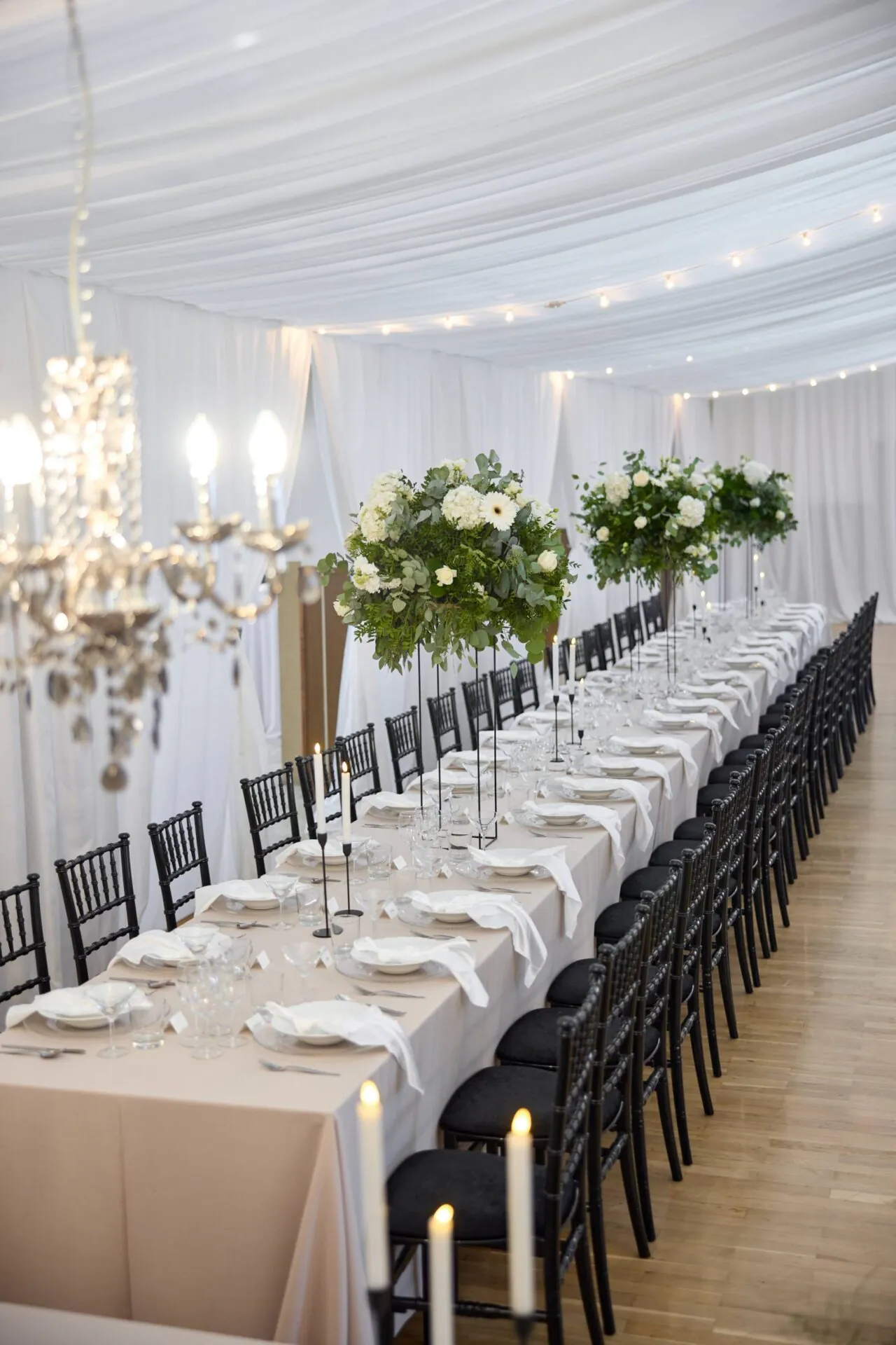 Dlhý svadobný stôl s čiernymi chiavari stoličkami a bielym obrusom