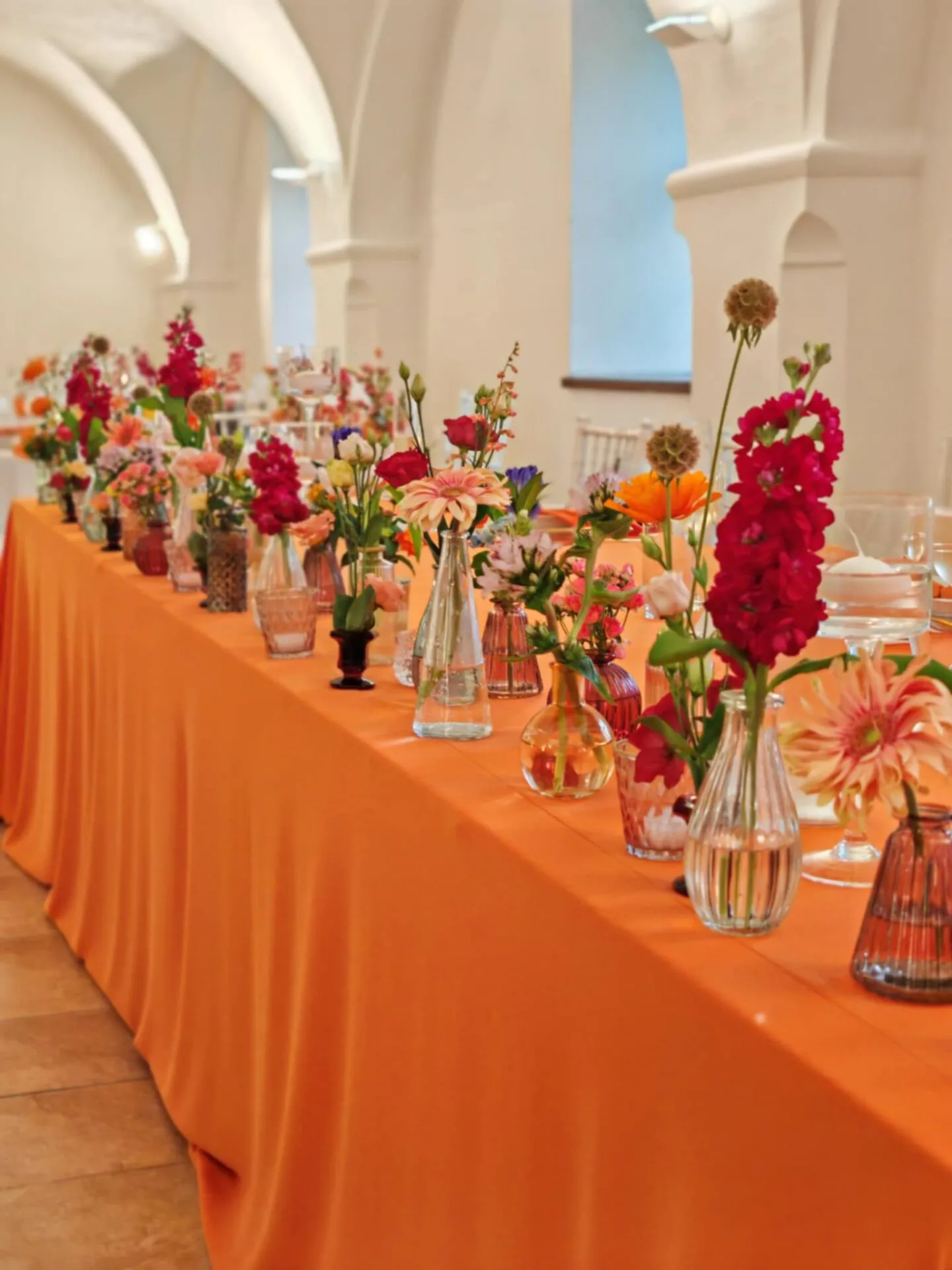 Svadobná výzdoba s farebnými kvetmi a oranžovým obrusom