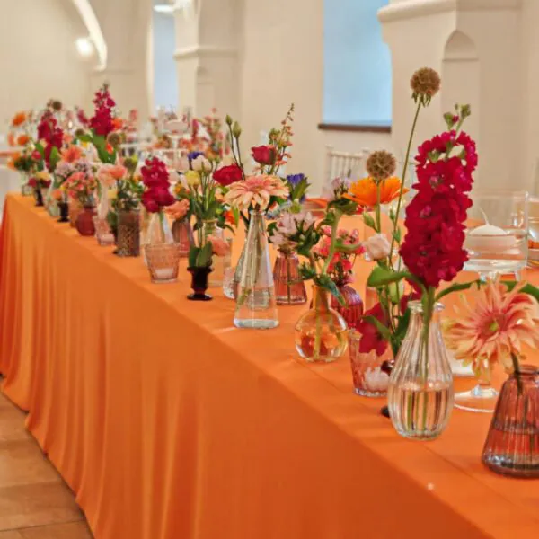 Svadobná výzdoba s farebnými kvetmi a oranžovým obrusom